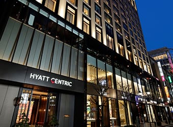 Exterior view of Hyatt Centric hotel building at twilight with illuminated windows.