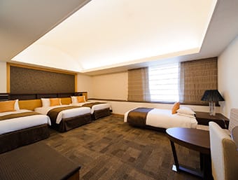 a hotel room with four beds and a desk.