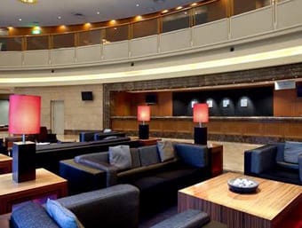 Modern hotel lobby with plush seating and a balcony above.