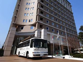 a white bus parked in front of a tall building.