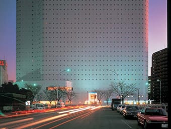 a city street with a tall building in the background.