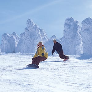 two snowboarders are going down a snowy hill.